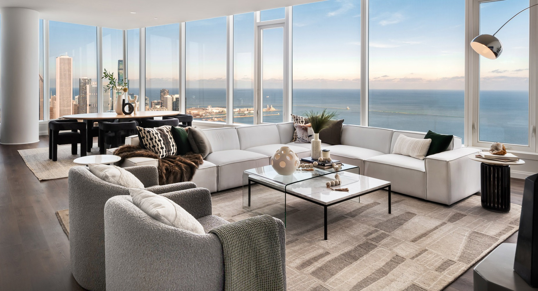 Sophisticated penthouse living room with white sectional, designer décor, and sweeping Lake Michigan and Chicago skyline views at 1000M Apartments