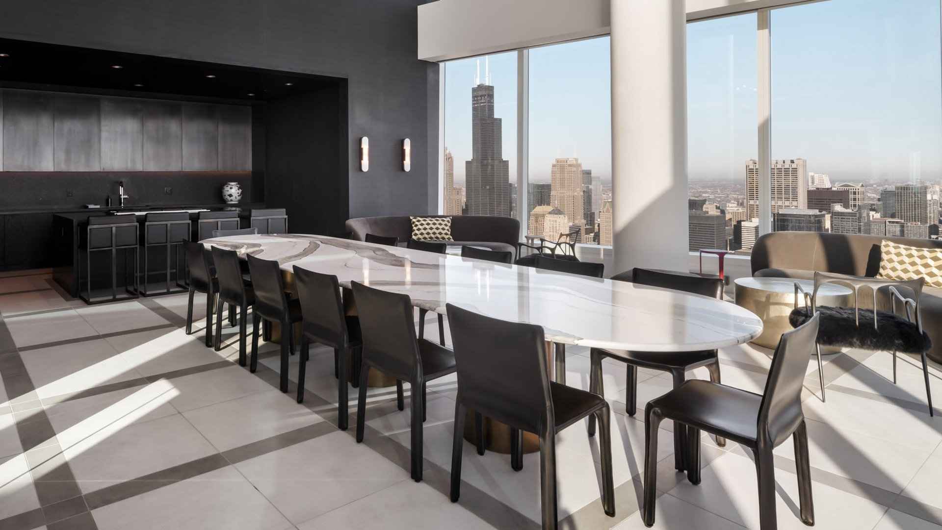 Elegant private dining room with long marble table, catering bar, and soaring windows framing Chicago skyline views at 1000M Apartments