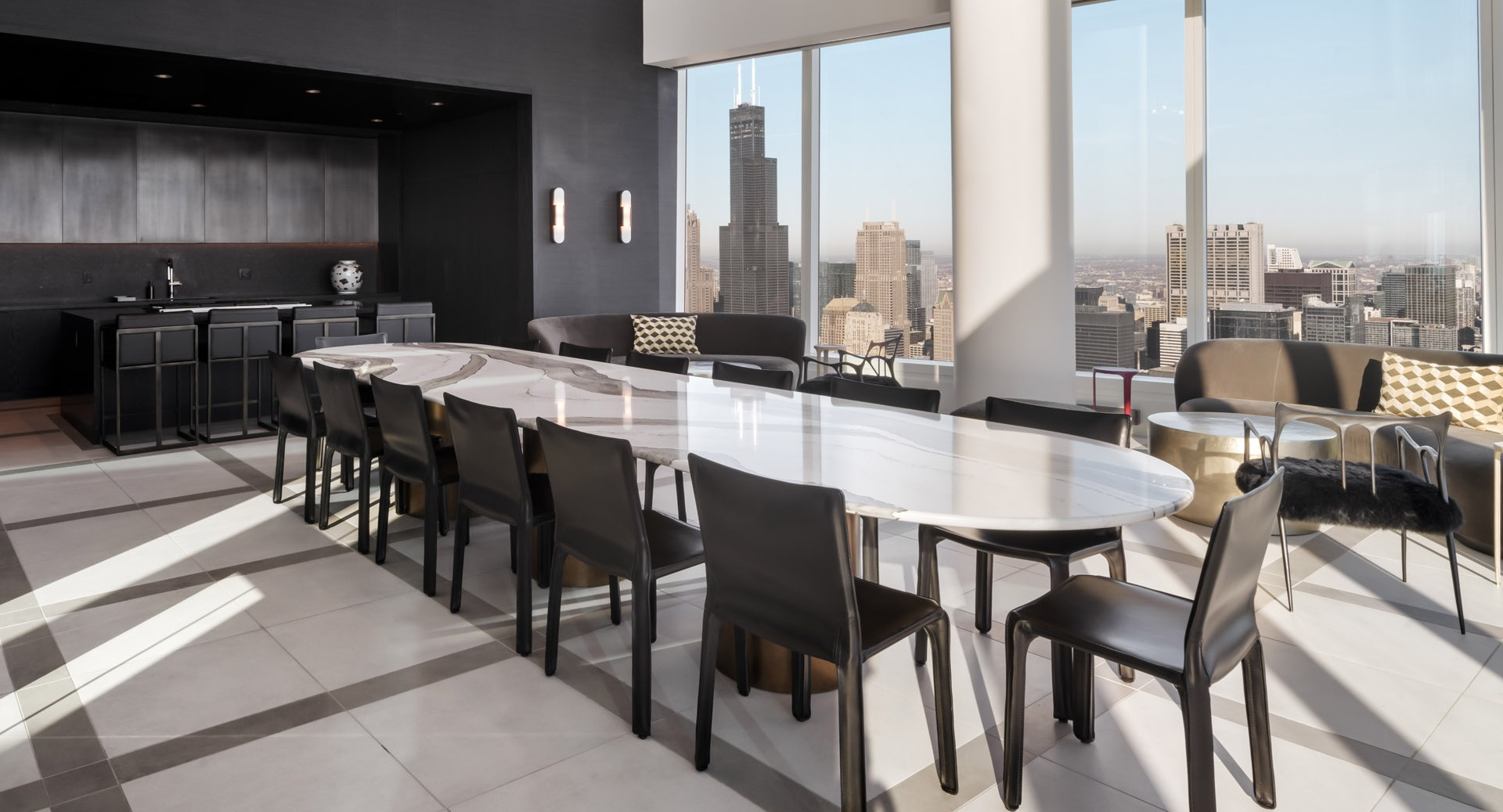 Elegant private dining room with long marble table, catering bar, and soaring windows framing Chicago skyline views at 1000M Apartments