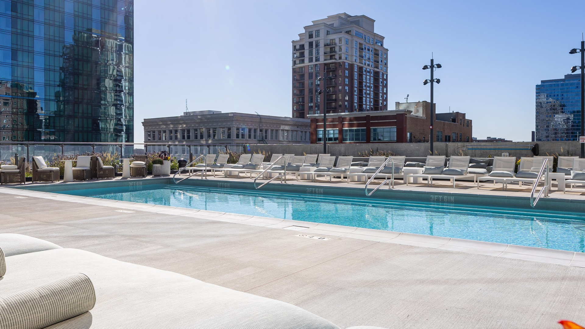 Rooftop pool with lounge chairs, skyline backdrop, and wide sun deck offering resort-style relaxation at 1000M Apartments in downtown Chicago