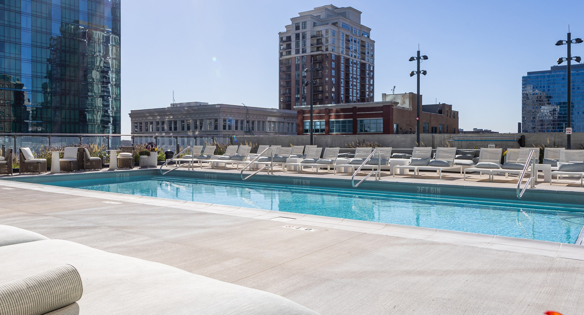 Rooftop pool with lounge chairs, skyline backdrop, and wide sun deck offering resort-style relaxation at 1000M Apartments in downtown Chicago