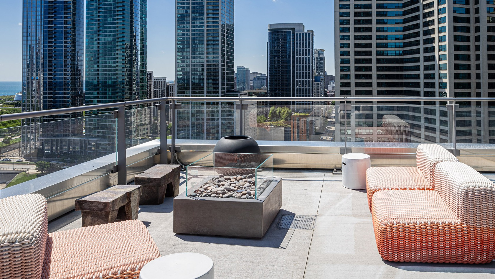 Outdoor terrace with woven seating, fire pit, and panoramic views of downtown Chicago skyscrapers at 1000M Apartments