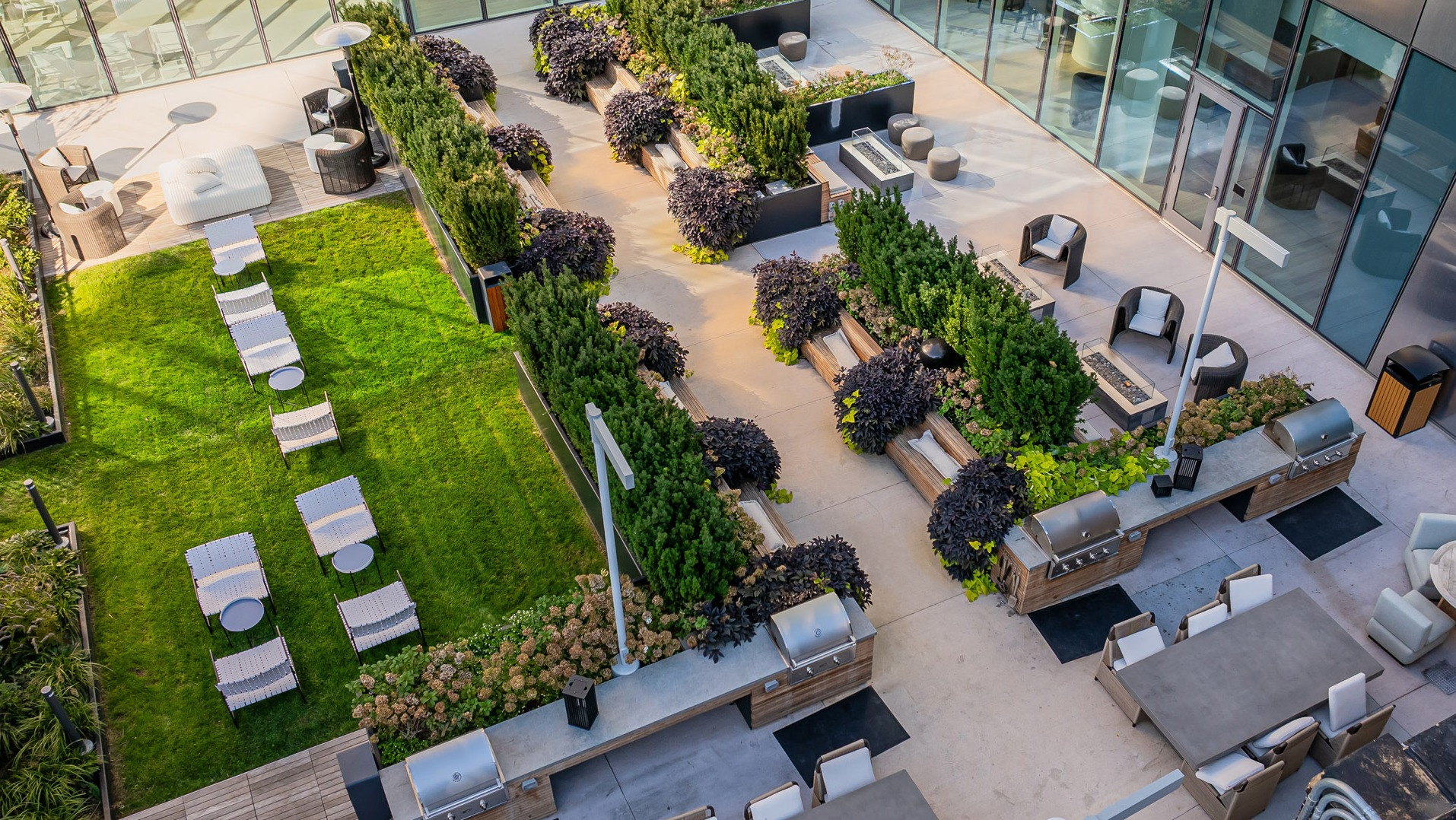 Elevated outdoor social garden featuring grilling stations, fire tables, landscaped seating zones, and lawn loungers at 1000M Apartments in Chicago
