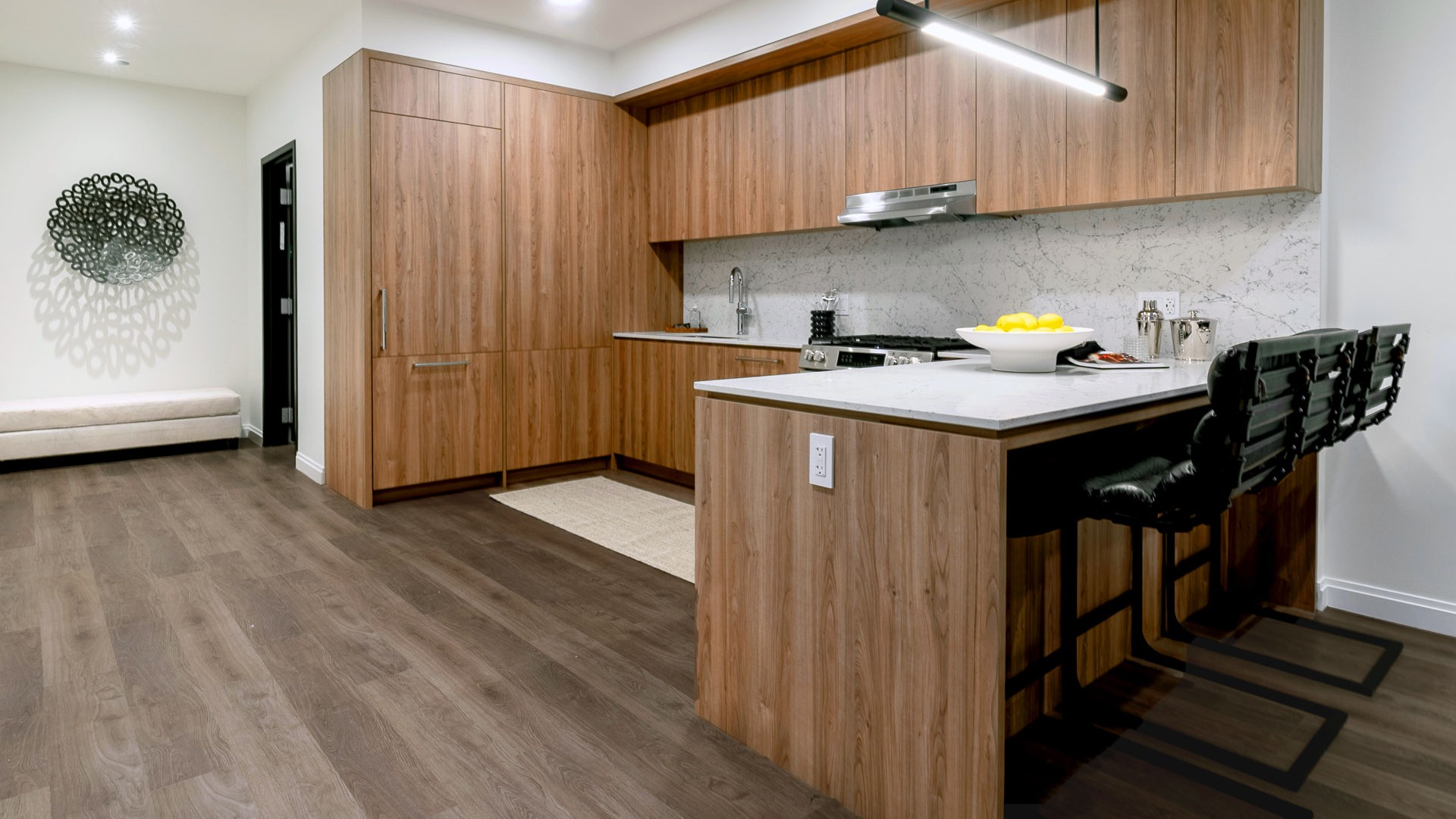 Spacious apartment kitchen with wood cabinetry, marble counters, and breakfast bar seating at 1000M Apartments in Chicago