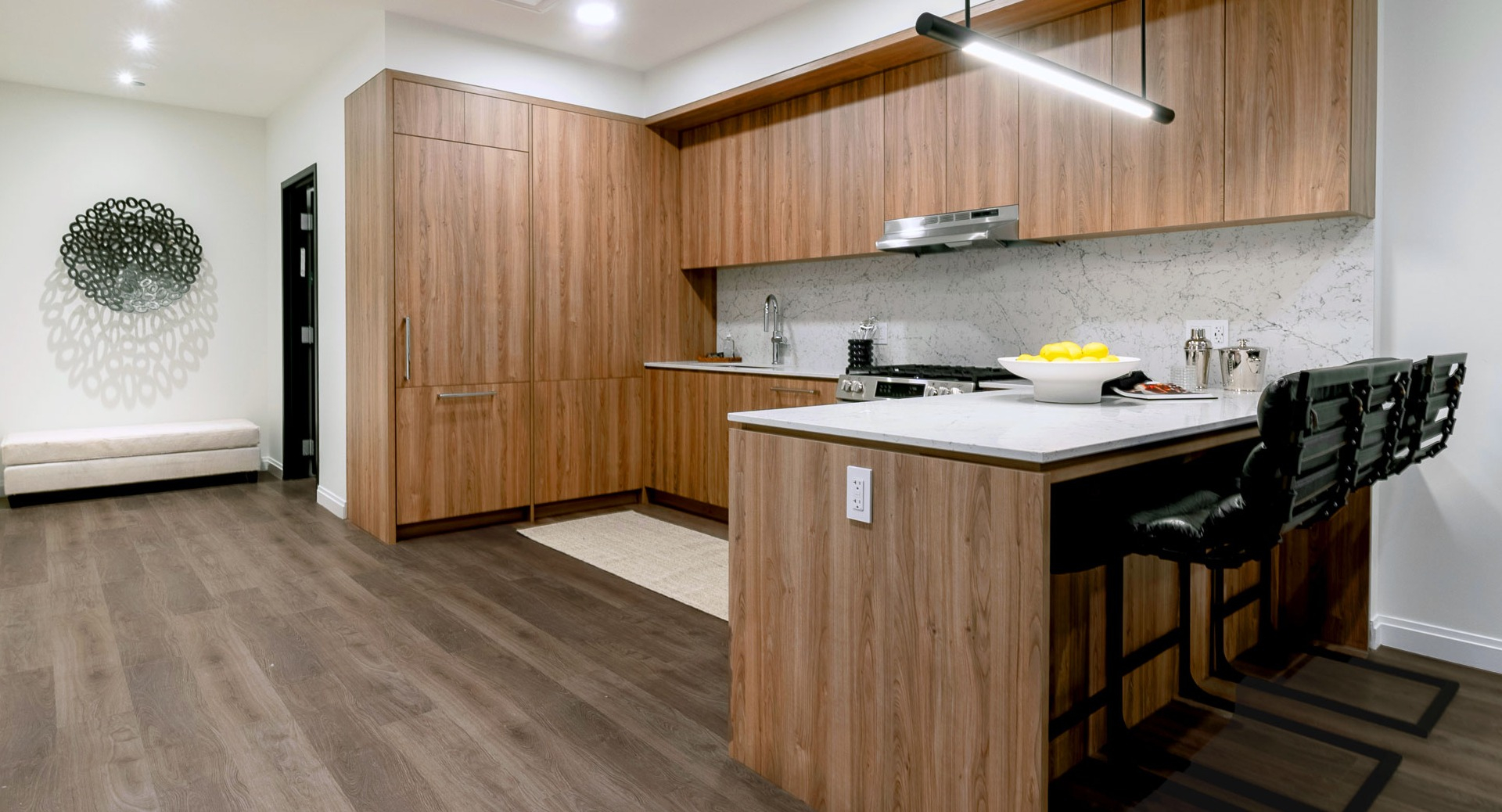 Spacious apartment kitchen with wood cabinetry, marble counters, and breakfast bar seating at 1000M Apartments in Chicago