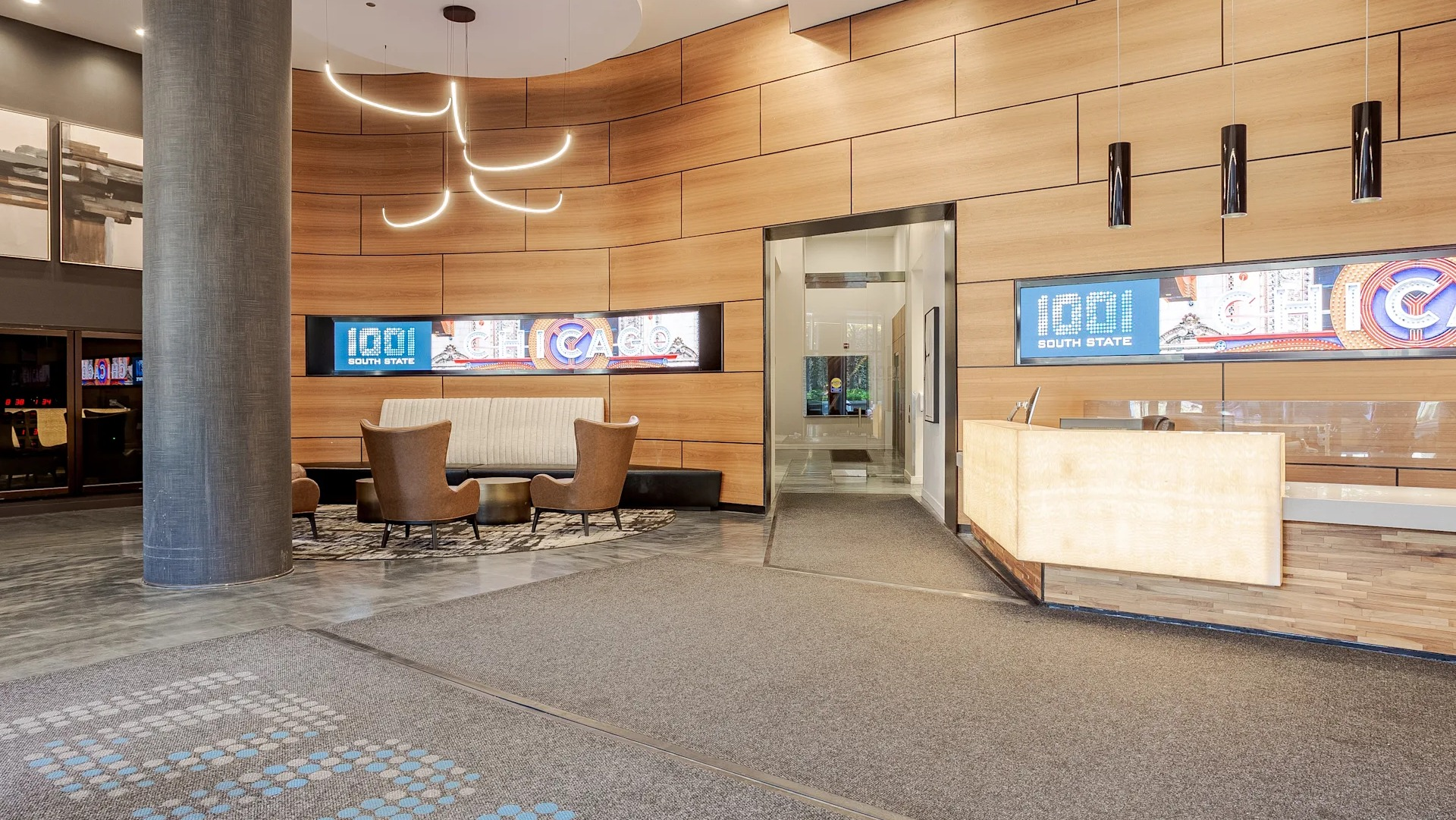 Stylish lobby at 1001 South State with wood accent walls, modern lighting, a welcoming front desk, and cozy seating areas in Chicago
