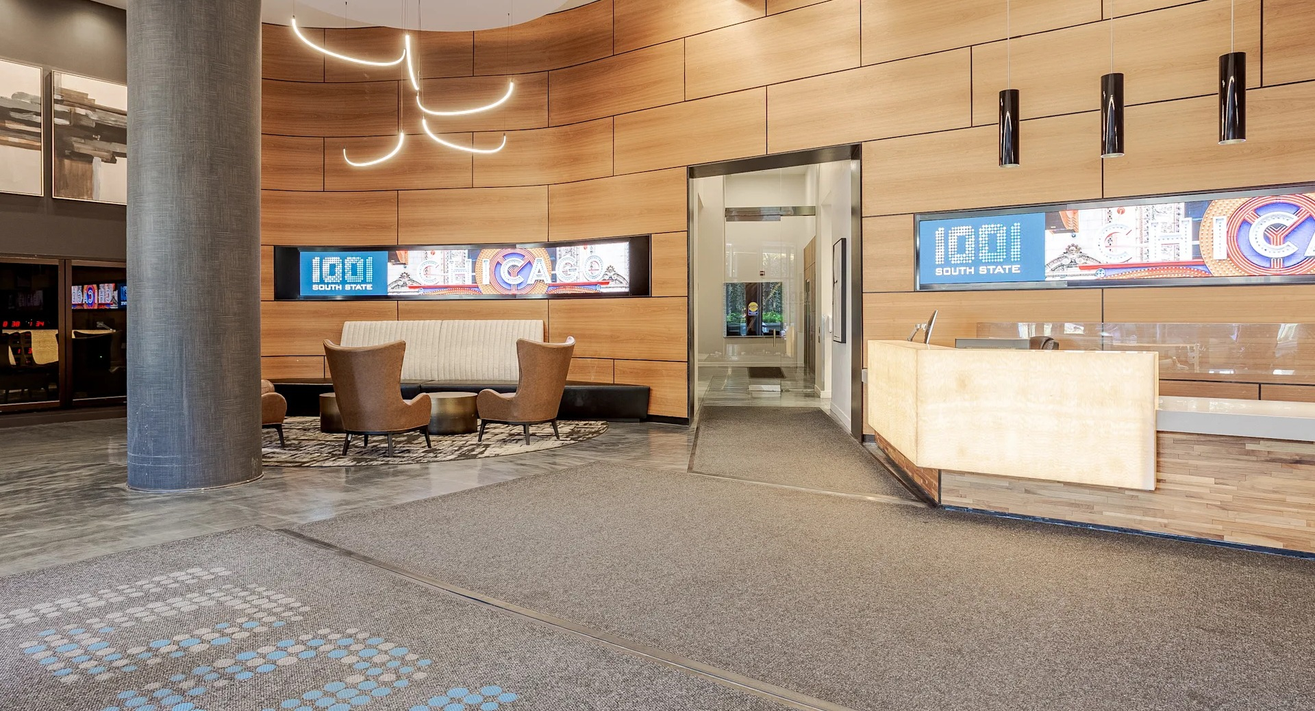 Stylish lobby at 1001 South State with wood accent walls, modern lighting, a welcoming front desk, and cozy seating areas in Chicago