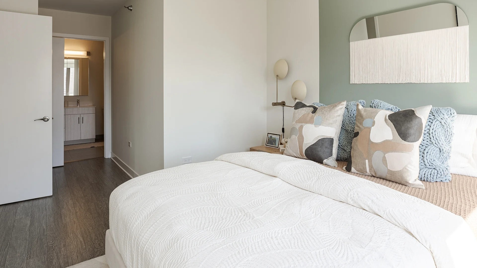 Cozy modern bedroom with soft neutral décor and direct access to bathroom at 1001 South State apartments in Chicago