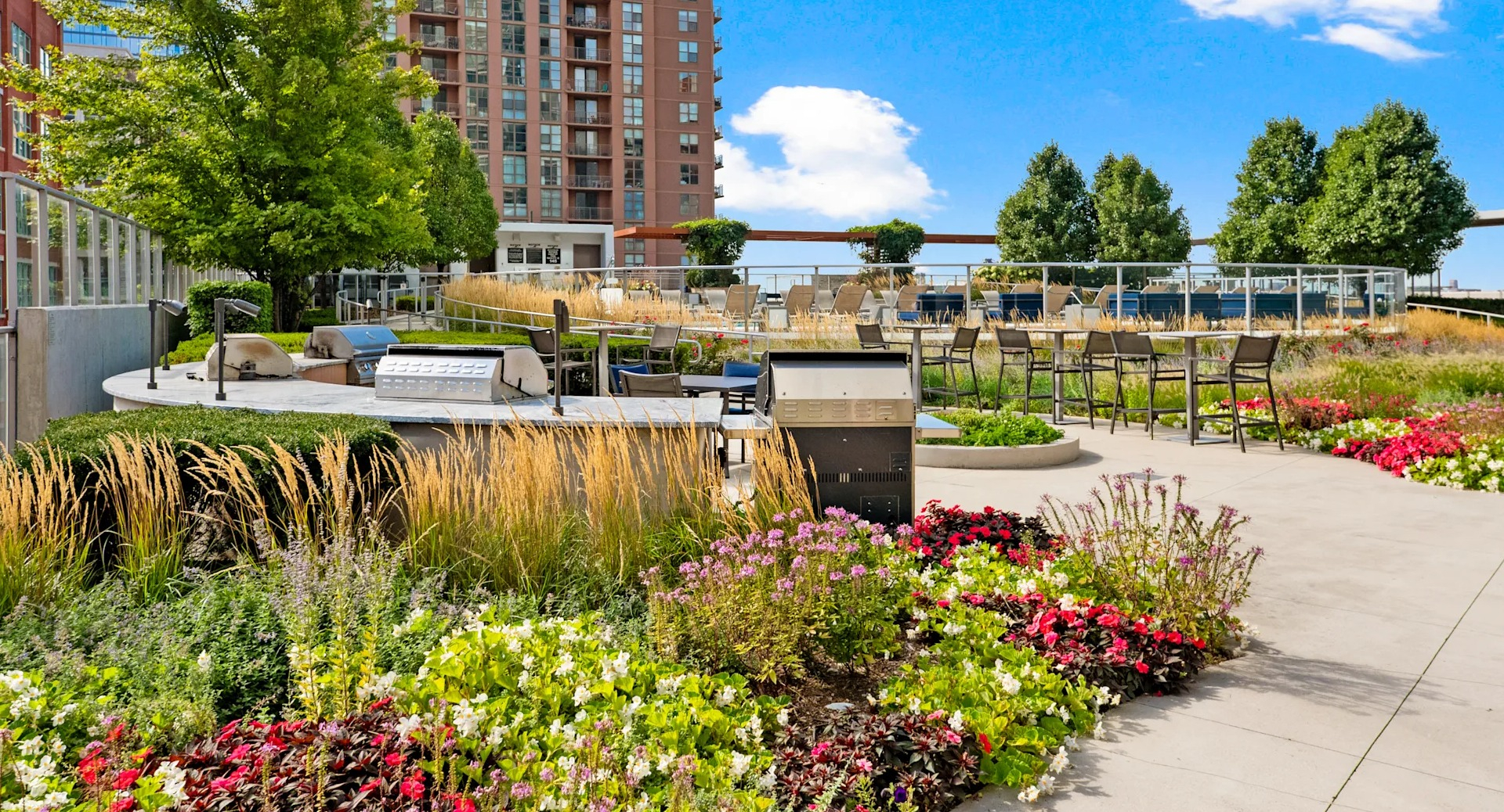 Landscaped terrace with outdoor grills, colorful flowers, and seating areas at 1001 South State apartments in Chicago