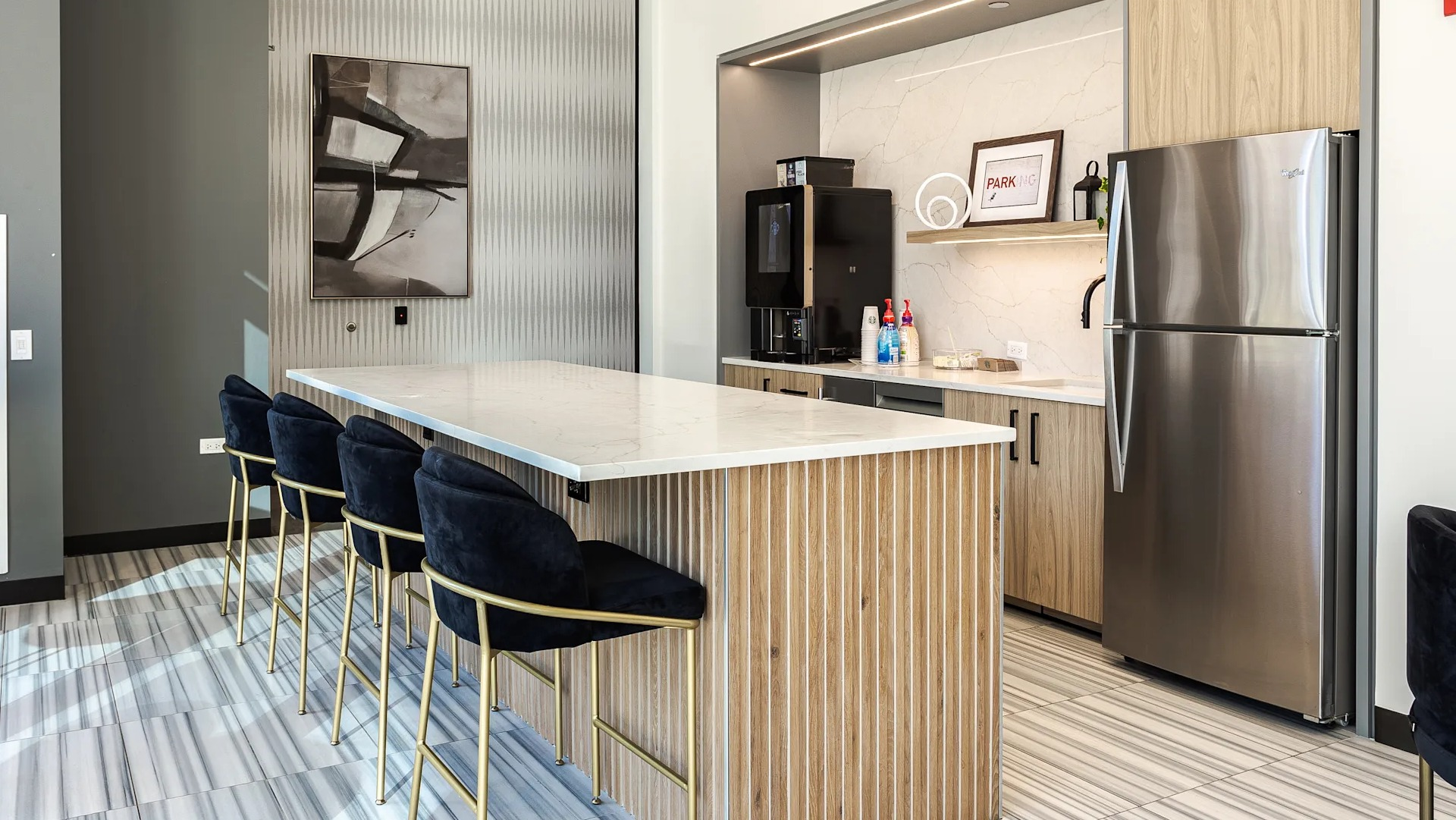 Contemporary kitchen and bar lounge with sleek countertops, stainless steel appliances, and seating at 1001 South State apartments