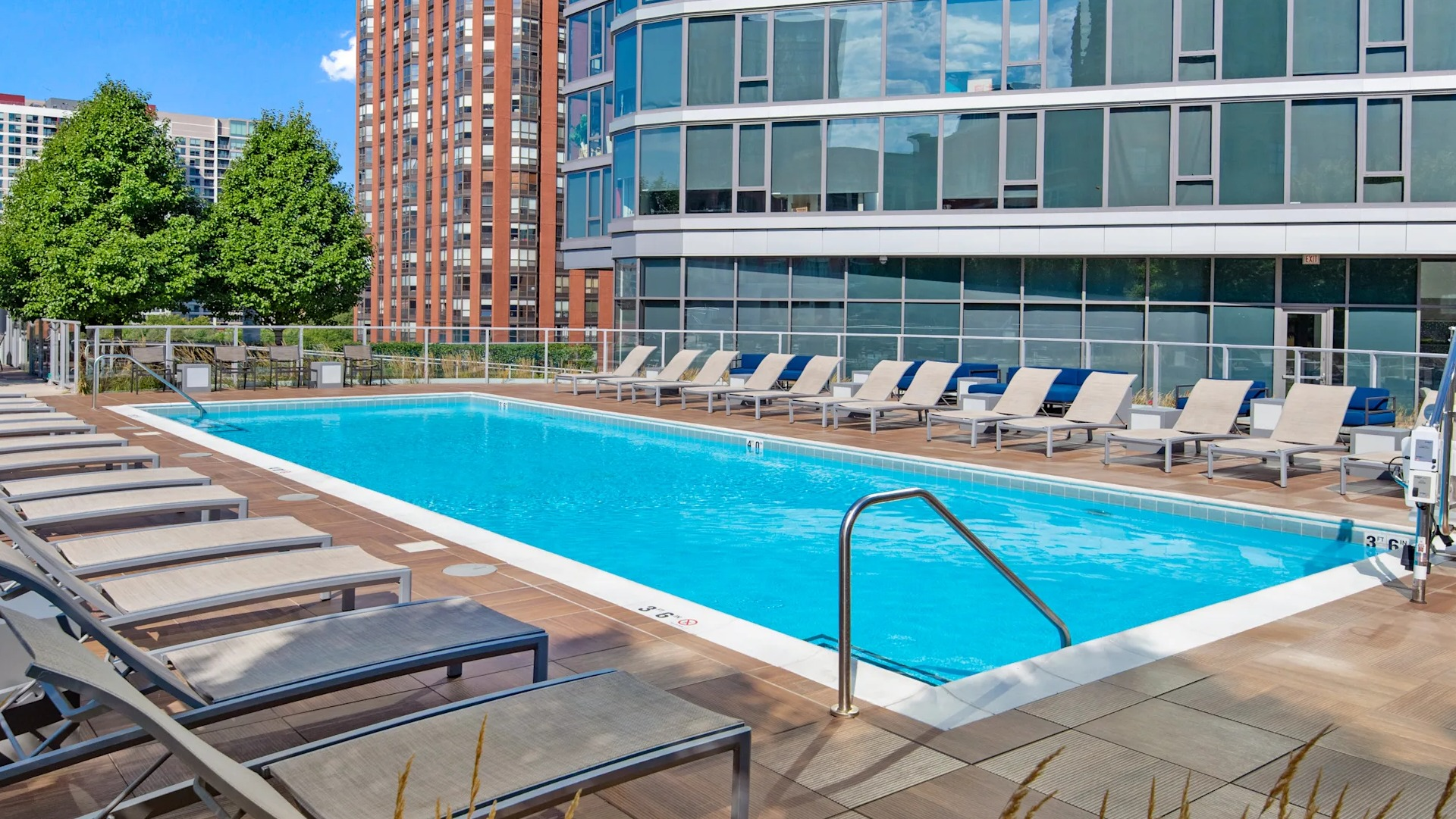 Outdoor pool with lounge chairs, wood deck, and skyline views at 1001 South State apartments in Chicago