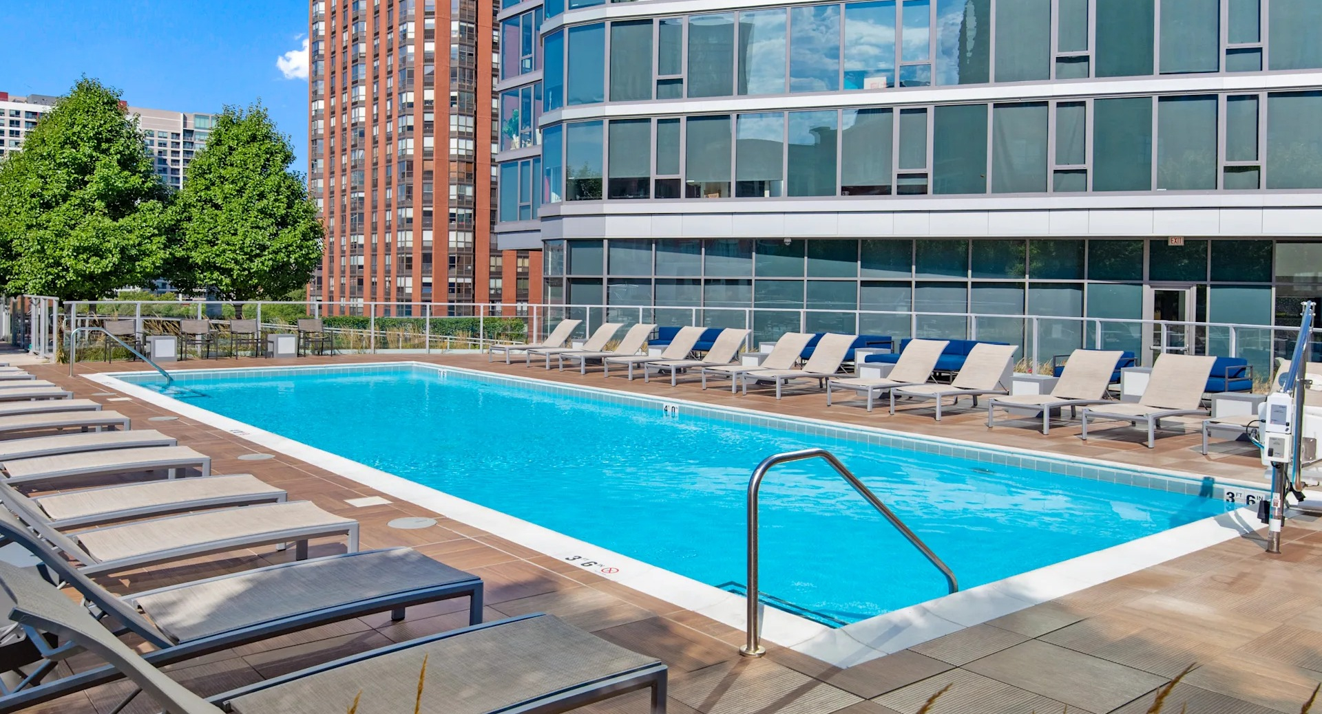 Outdoor pool with lounge chairs, wood deck, and skyline views at 1001 South State apartments in Chicago