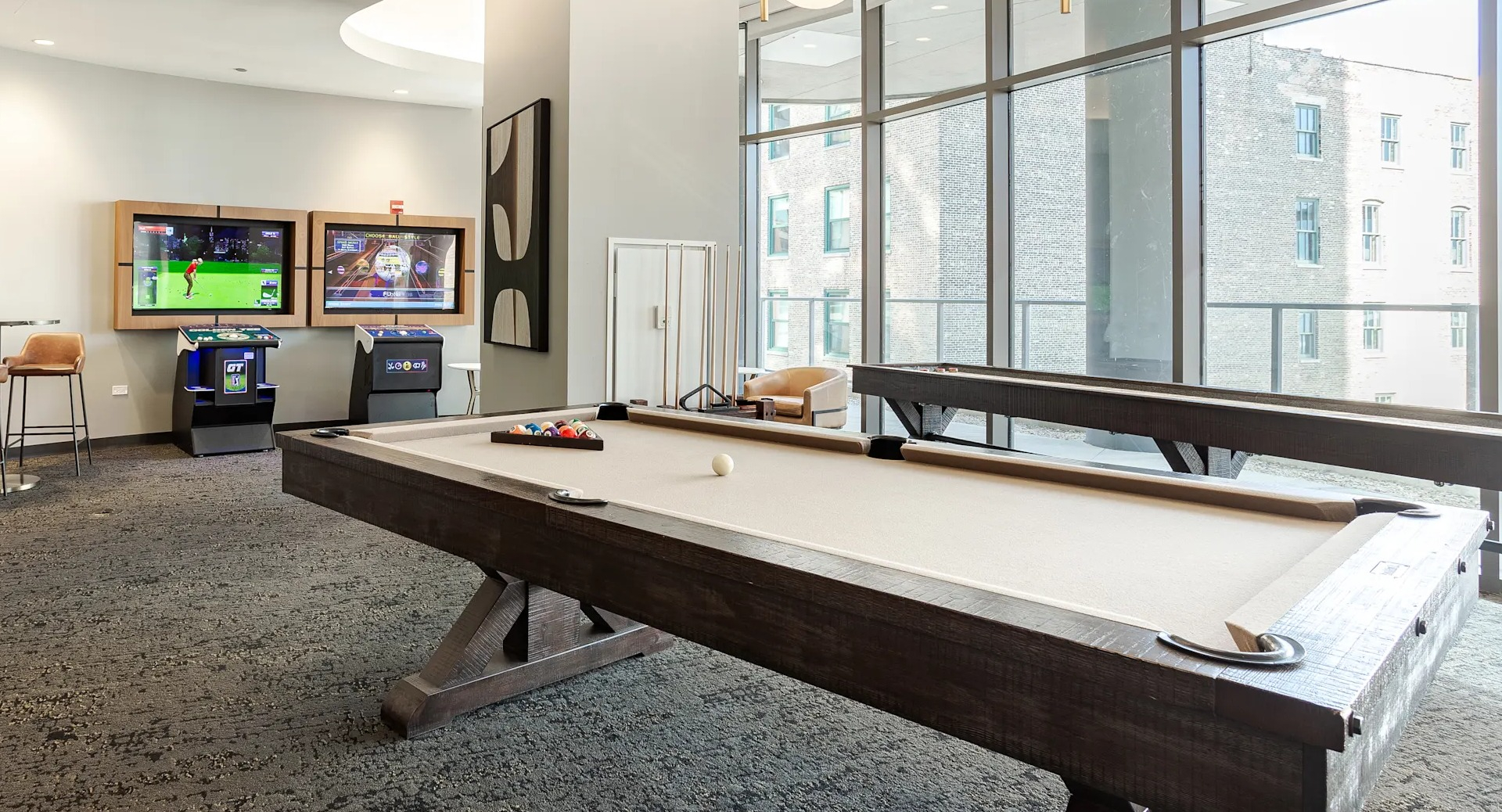 Resident game room with pool table, lounge seating, and entertainment screens at 1001 South State apartments in Chicago