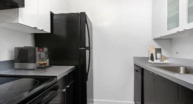 U-shaped kitchen with espresso cabinetry, black microwave and dishwasher at 1100 North Dearborn apartments in Chicago