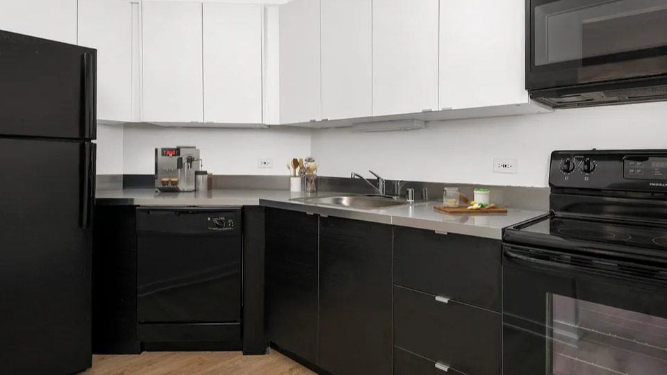 Contemporary black-and-white kitchen at 1111 N Dearborn with stainless counters and black appliances—stylish, easy-care workspace in a Chicago apartment home