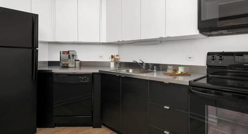 Contemporary black-and-white kitchen at 1111 N Dearborn with stainless counters and black appliances—stylish, easy-care workspace in a Chicago apartment home