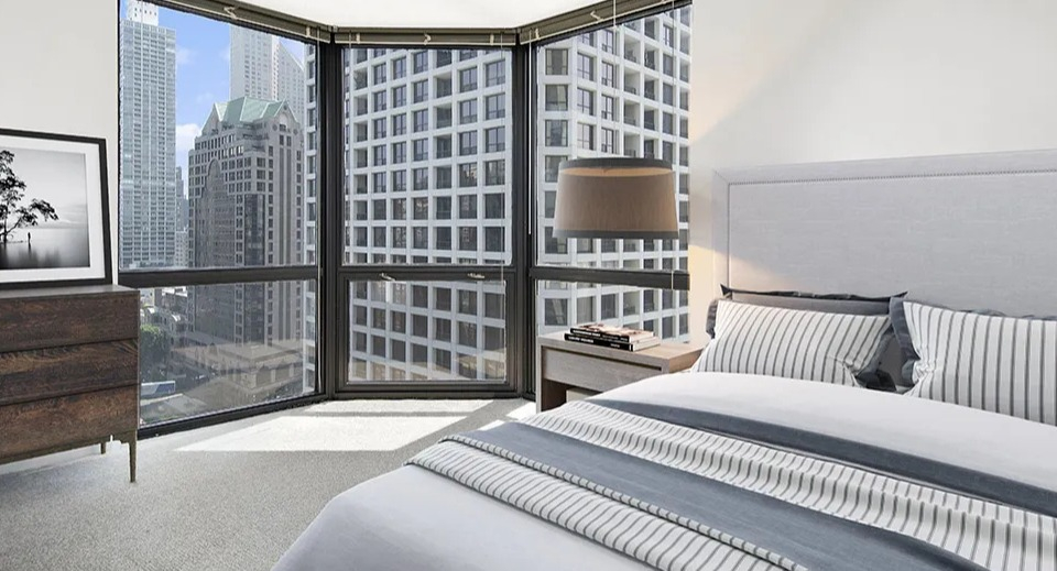 Corner bedroom at 1111 N Dearborn with floor-to-ceiling windows and skyline views, a dresser, and neutral décor—perfect for a modern Gold Coast apartment