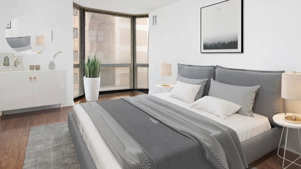 Minimalist bedroom at 1111 N Dearborn with wood floors, sleek gray bedding, and expansive windows with blinds—clean, modern style in a Chicago apartment