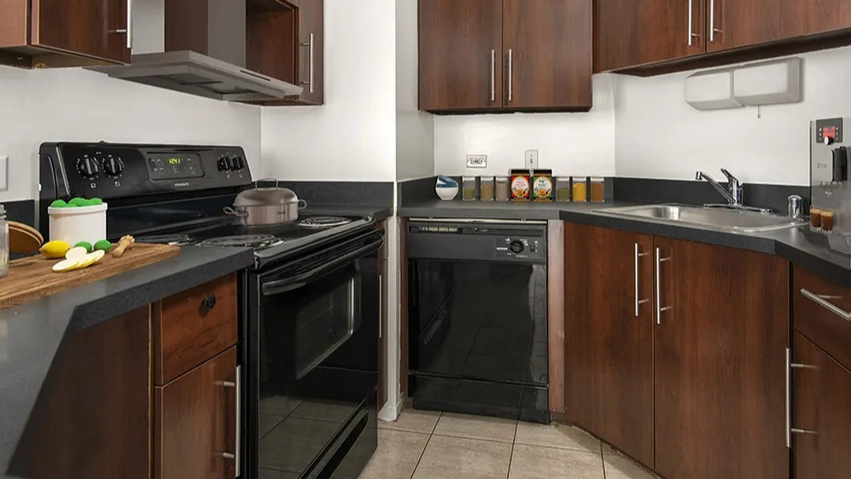 U-shaped kitchen at 1111 N Dearborn with dark wood cabinets, black appliances, and ample counter space—convenient cooking layout in a Chicago apartment