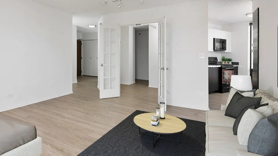 Bright bedroom with sofa, bed, French doors, and access to a modern kitchen at 1120 N LaSalle apartments in Chicago