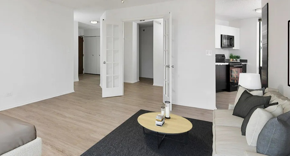 Bright bedroom with sofa, bed, French doors, and access to a modern kitchen at 1120 N LaSalle apartments in Chicago