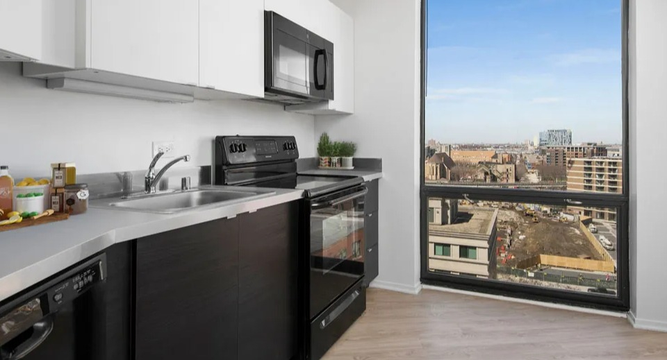 Modern galley kitchen with black appliances, microwave, and a large picture window overlooking the city at 1120 N LaSalle in Chicago