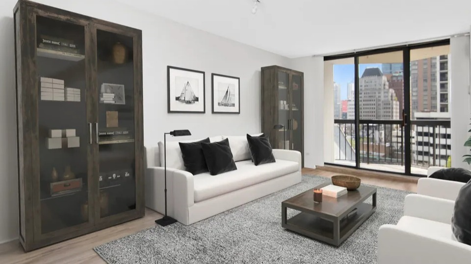 Bright living room with two sofas, glass cabinets, and a balcony with floor-to-ceiling windows at 1120 N LaSalle apartments in Chicago