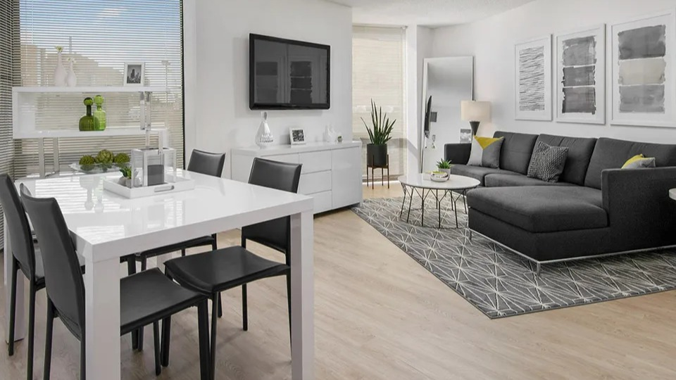Modern living and dining area with a sleek white table, black chairs, sectional sofa, and large windows at 1120 N LaSalle apartments in Chicago