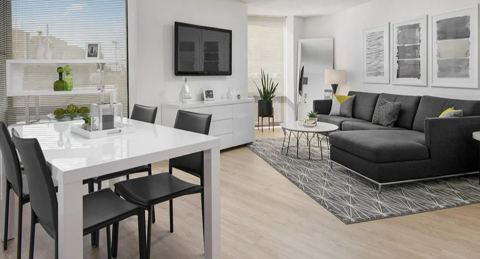 Modern living and dining area with a sleek white table, black chairs, sectional sofa, and large windows at 1120 N LaSalle apartments in Chicago
