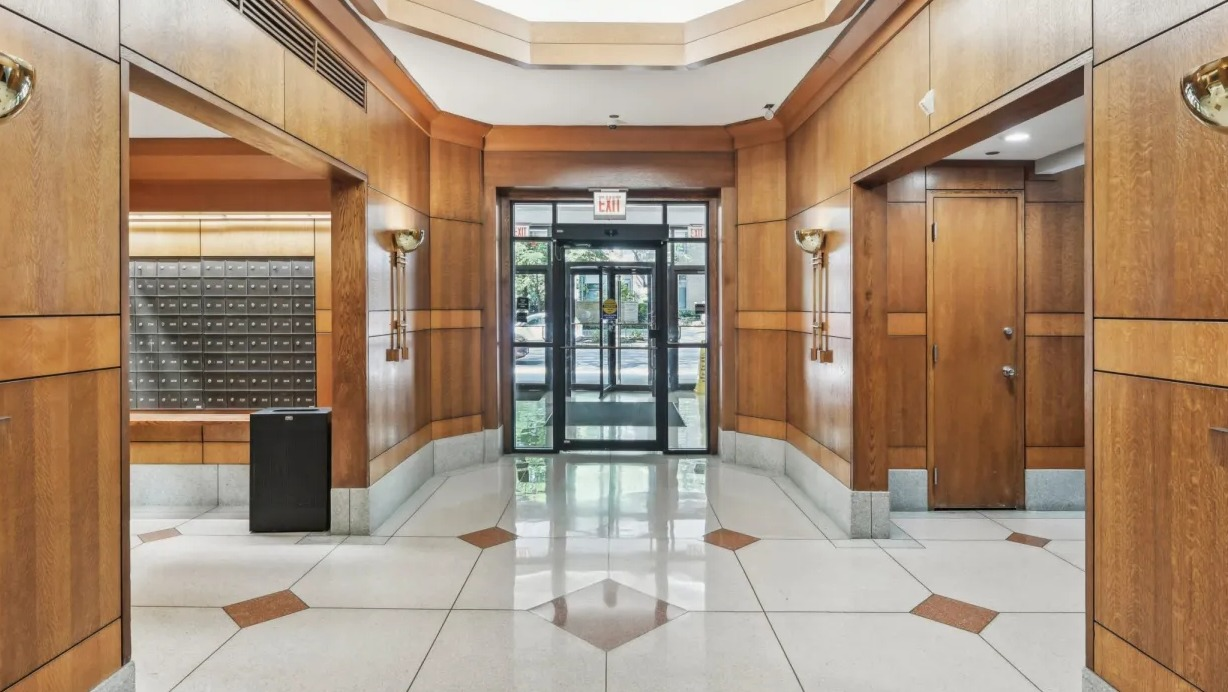 Elegant lobby entrance with warm wood paneling, geometric tile floors, sconces, and mailroom access at 1133 N Dearborn apartments in Chicago