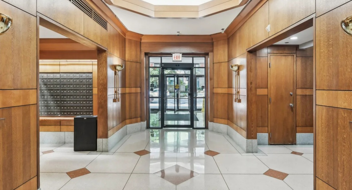 Elegant lobby entrance with warm wood paneling, geometric tile floors, sconces, and mailroom access at 1133 N Dearborn apartments in Chicago