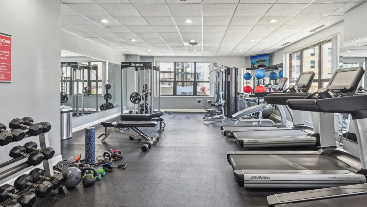 Well-equipped gym with multiple treadmills, cable machines, free weights, and large mirrors offering a convenient workout space at 1133 N Dearborn in Chicago
