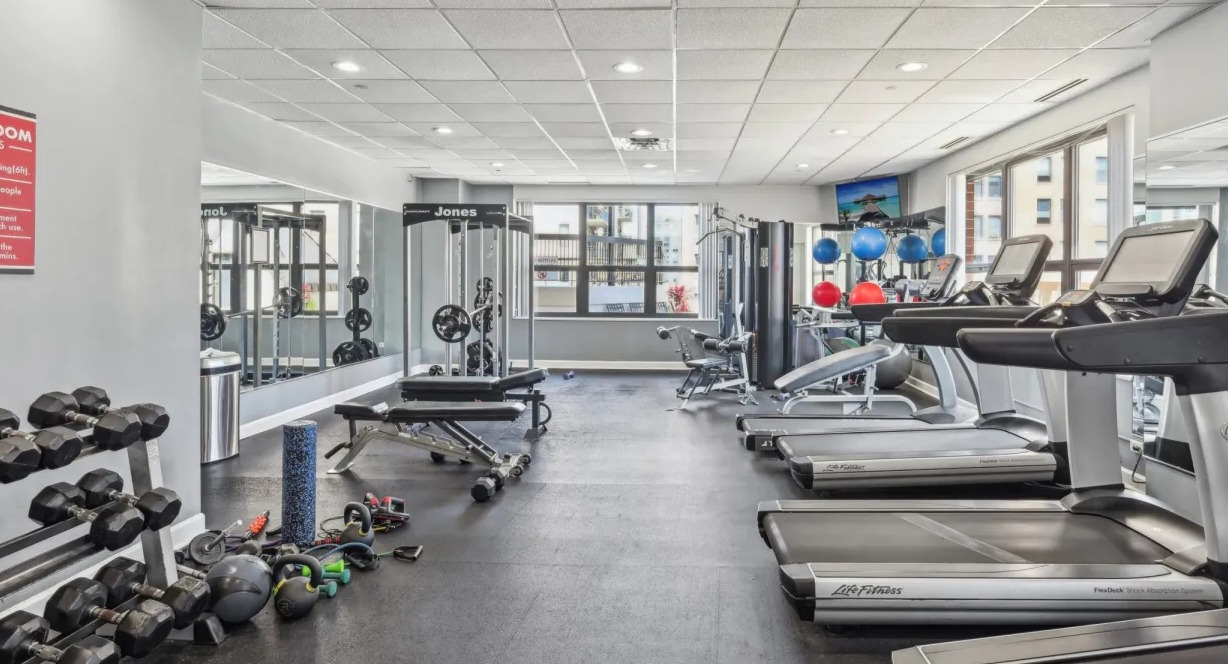 Well-equipped gym with multiple treadmills, cable machines, free weights, and large mirrors offering a convenient workout space at 1133 N Dearborn in Chicago