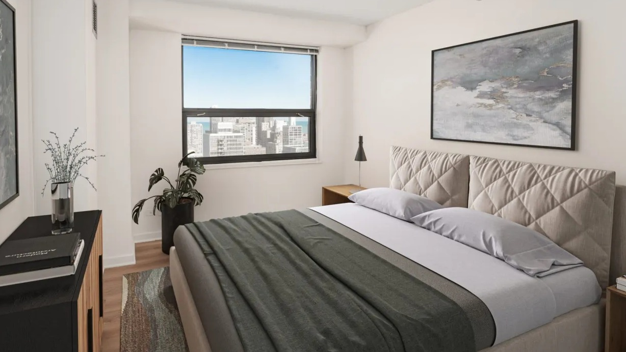 Bright modern bedroom with upholstered headboard, city and lake view window, neutral décor and wood floors at 1133 N Dearborn apartments in Chicago