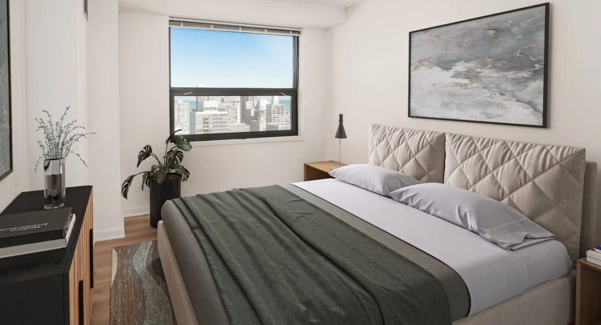 Bright modern bedroom with upholstered headboard, city and lake view window, neutral décor and wood floors at 1133 N Dearborn apartments in Chicago