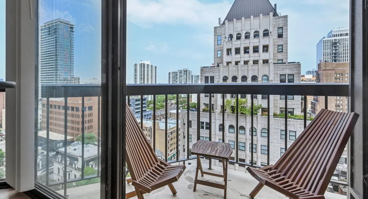 Private balcony with two lounge chairs and a small table overlooking classic and modern Chicago architecture at 1133 N Dearborn apartments