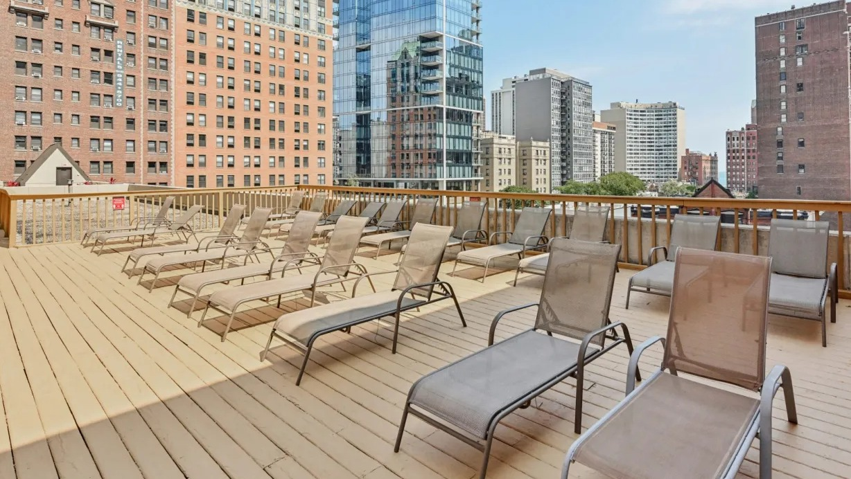 Expansive rooftop sundeck lined with chaise lounges and open skyline views, ideal for outdoor relaxing at 1133 N Dearborn apartments in Chicago