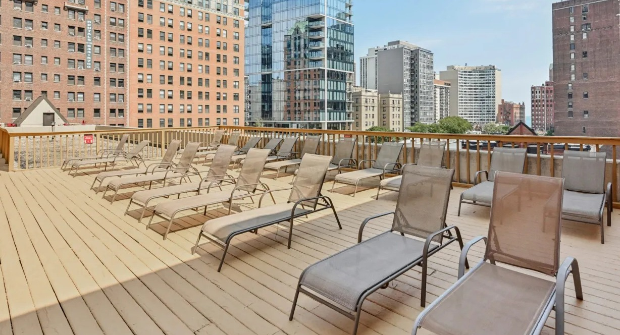 Expansive rooftop sundeck lined with chaise lounges and open skyline views, ideal for outdoor relaxing at 1133 N Dearborn apartments in Chicago