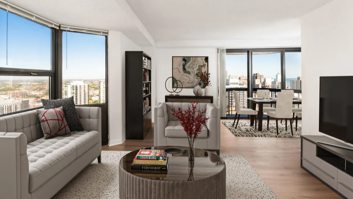 Spacious living room with large corner windows, contemporary seating, TV console, and open layout with dining area at 1133 N Dearborn apartments in Chicago