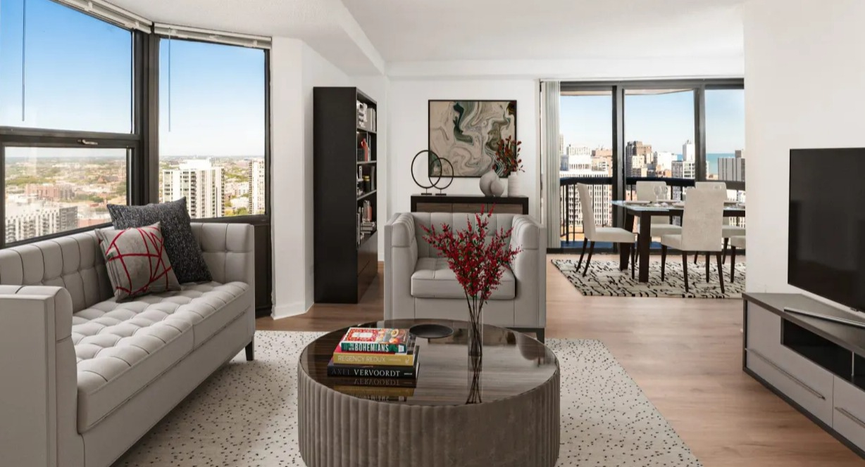 Spacious living room with large corner windows, contemporary seating, TV console, and open layout with dining area at 1133 N Dearborn apartments in Chicago