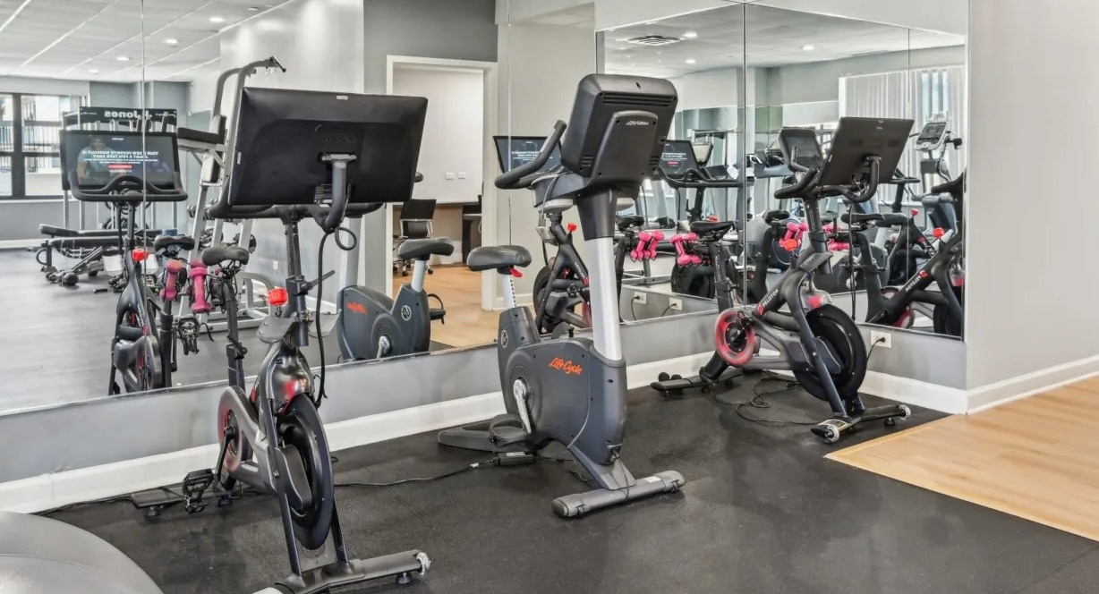 Spin studio corner with stationary bikes, mirrors, and nearby cardio equipment providing a focused workout area at 1133 N Dearborn apartments in Chicago