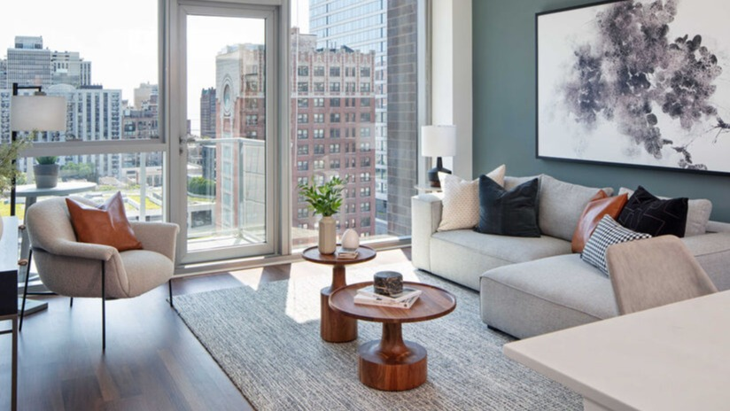 Bright living room with balcony door, skyline views, and stylish furnishings against a blue accent wall at 1225 Old Town Apartments in Chicago