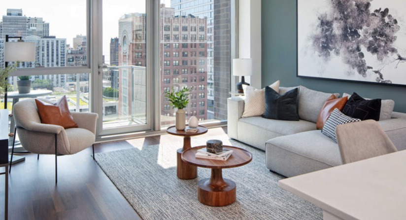 Bright living room with balcony door, skyline views, and stylish furnishings against a blue accent wall at 1225 Old Town Apartments in Chicago