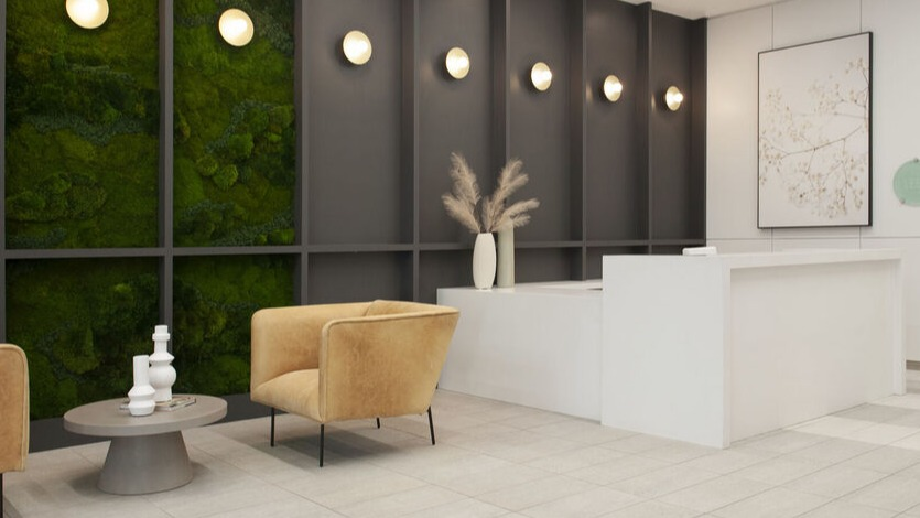 Contemporary lobby with green moss accent wall, warm lounge chairs, and bright reception desk at 1225 Old Town Apartments in Chicago