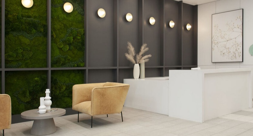Contemporary lobby with green moss accent wall, warm lounge chairs, and bright reception desk at 1225 Old Town Apartments in Chicago