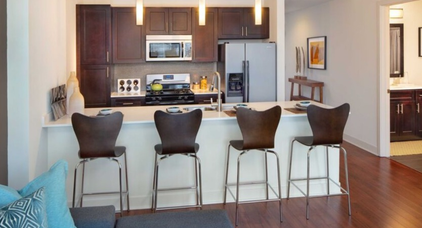 Modern kitchen with breakfast bar, dark cabinets, stainless appliances, and pendant lighting at 1225 Old Town Apartments in Chicago