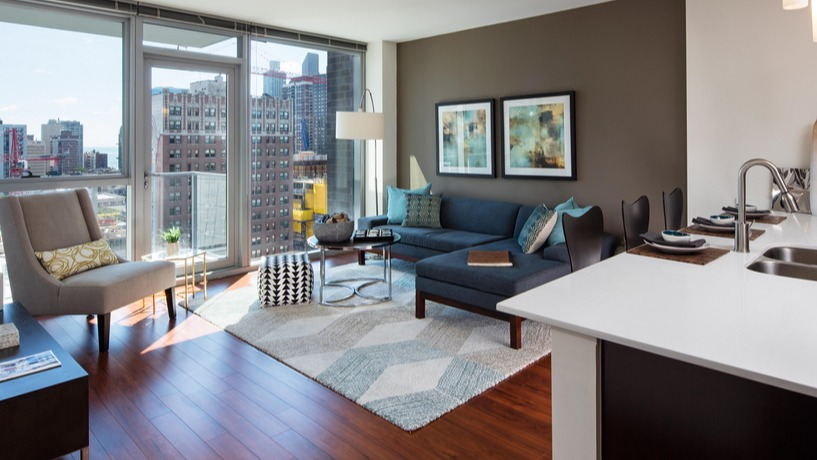 Open-concept living room with floor-to-ceiling windows, modern kitchen island, and skyline views at 1225 Old Town Apartments in Chicago