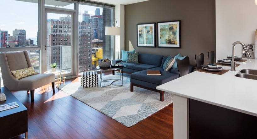 Open-concept living room with floor-to-ceiling windows, modern kitchen island, and skyline views at 1225 Old Town Apartments in Chicago