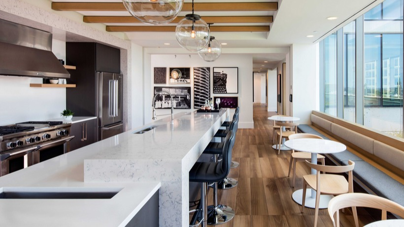 Rooftop lounge and demonstration kitchen with long marble island, pendant lights, and window seating at 1225 Old Town Apartments in Chicago