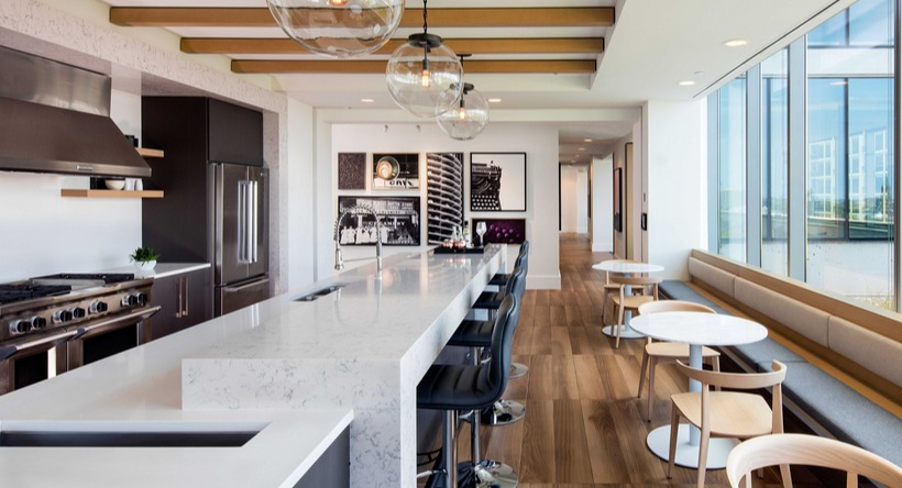 Rooftop lounge and demonstration kitchen with long marble island, pendant lights, and window seating at 1225 Old Town Apartments in Chicago